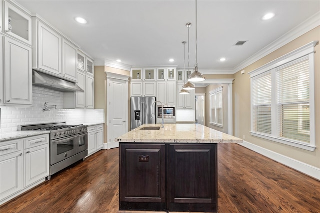 428 W 26th St, Houston, TX 77008 - kitchen featuring high quality appliances, under cabinet range hood, white cabinetry, ornamental molding, and decorative backsplash