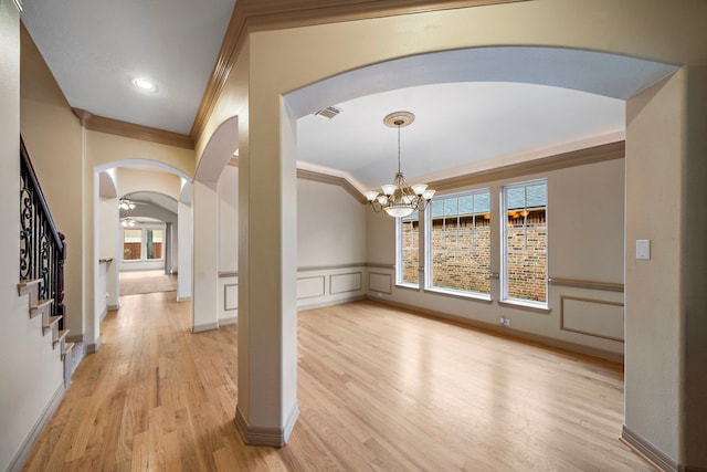6823 Rosemont Park Ln, Katy, TX 77494 - foyer featuring arched walkways, ornamental molding, a chandelier, light wood-style flooring, and a wainscoted wall