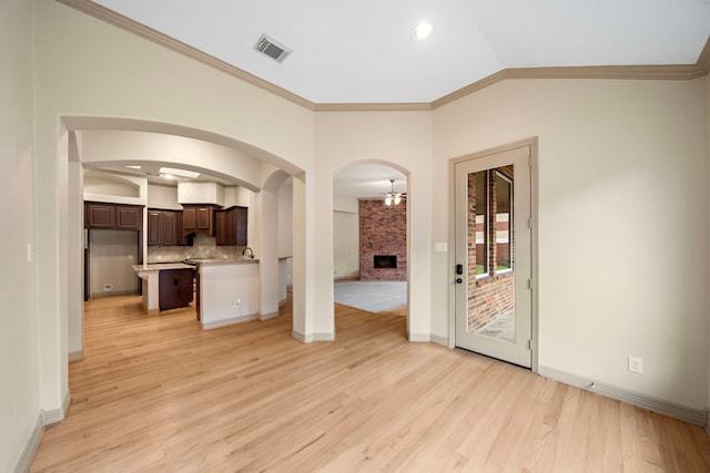 6823 Rosemont Park Ln, Katy, TX 77494 - unfurnished living room featuring light wood-style floors, a fireplace, ornamental molding, baseboards, and vaulted ceiling