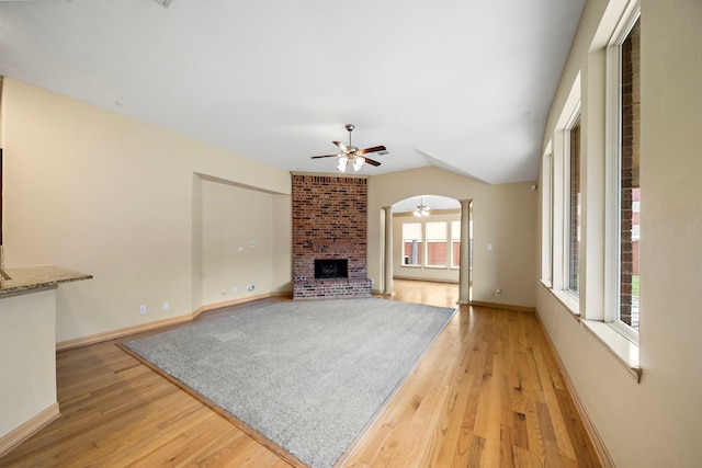 6823 Rosemont Park Ln, Katy, TX 77494 - unfurnished living room with light wood-style floors, a ceiling fan, a brick fireplace, baseboards, and lofted ceiling