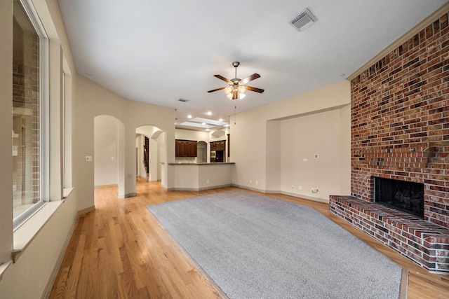 6823 Rosemont Park Ln, Katy, TX 77494 - unfurnished living room featuring arched walkways, ceiling fan, light wood finished floors, a fireplace, and baseboards