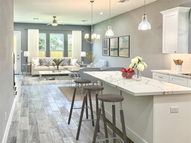 6804 Foster St, Houston, TX 77021 - kitchen with white cabinets, a breakfast bar area, a center island, ceiling fan, and open floor plan