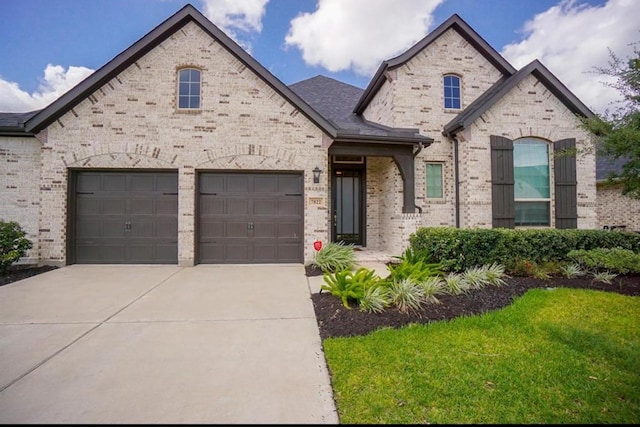 7822 Taronga Ln, Richmond, TX 77407 - french country inspired facade featuring driveway, brick siding, a front yard, and a garage