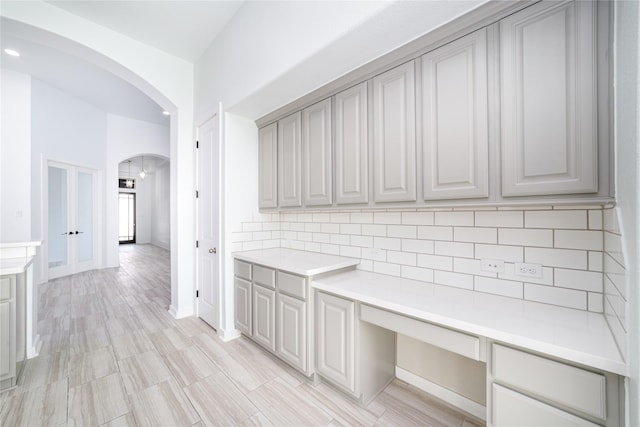 7822 Taronga Ln, Richmond, TX 77407 - kitchen with arched walkways, tasteful backsplash, gray cabinetry, and light countertops
