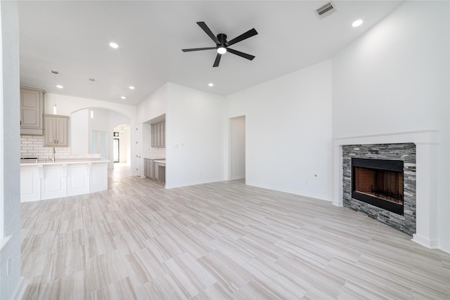 7822 Taronga Ln, Richmond, TX 77407 - unfurnished living room featuring ceiling fan, recessed lighting, a stone fireplace, arched walkways, and light wood-style flooring