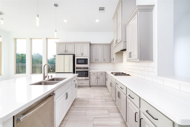 7822 Taronga Ln, Richmond, TX 77407 - kitchen featuring stainless steel appliances, a sink, decorative backsplash, decorative light fixtures, and light countertops