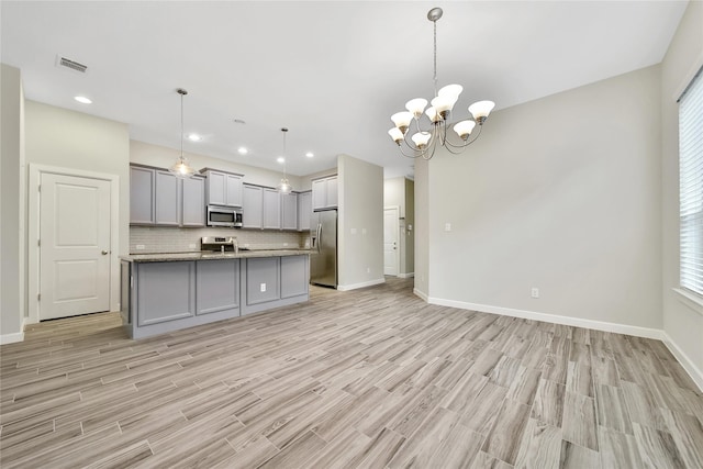 117 Saddle Dr, Houston, TX 77065 - kitchen with appliances with stainless steel finishes, gray cabinetry, light wood-style flooring, open floor plan, and backsplash
