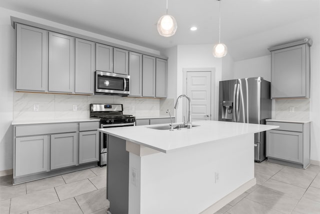 7414 Keystone Blossom Trl, Richmond, TX 77407 - kitchen featuring appliances with stainless steel finishes, gray cabinets, a sink, tasteful backsplash, and a center island with sink