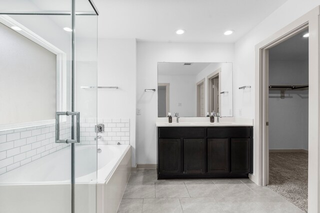 7414 Keystone Blossom Trl, Richmond, TX 77407 - bathroom featuring a bath, double vanity, tile patterned floors, a walk in closet, and baseboards