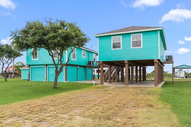 621 County Road 202, Sargent, TX 77414 - back of property featuring cooling unit, stairway, a lawn, and a shingled roof
