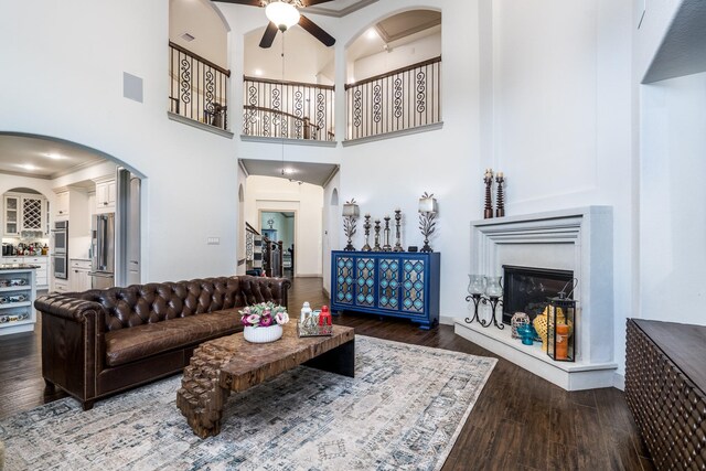18815 Ellis Bend Dr, Cypress, TX 77433 - living area featuring arched walkways, a ceiling fan, wood finished floors, a glass covered fireplace, and a high ceiling