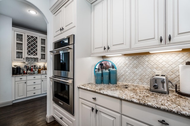 18815 Ellis Bend Dr, Cypress, TX 77433 - kitchen with double oven, decorative backsplash, glass insert cabinets, dark wood-style floors, and white cabinets