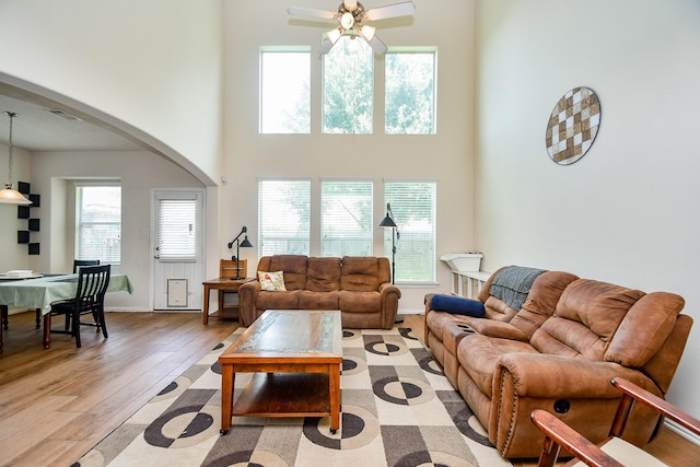 2818 Lakecrest Forest Dr, Katy, TX 77493 - living area featuring arched walkways, ceiling fan, light wood-type flooring, a towering ceiling, and baseboards