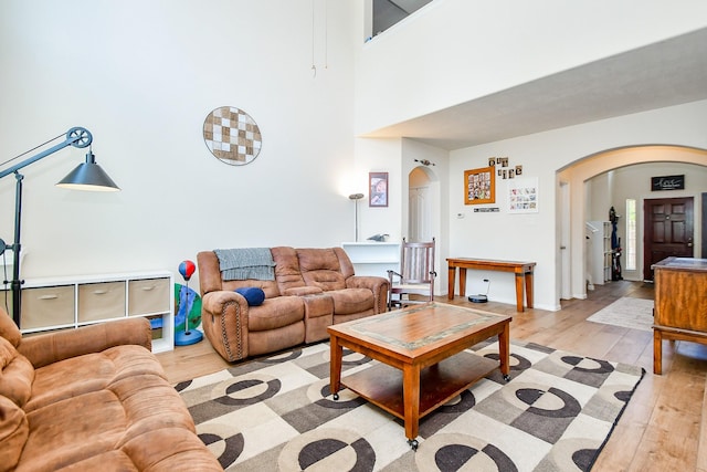 2818 Lakecrest Forest Dr, Katy, TX 77493 - living room featuring arched walkways, light wood-style flooring, and a towering ceiling