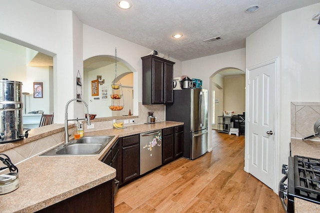 2818 Lakecrest Forest Dr, Katy, TX 77493 - kitchen with a sink, appliances with stainless steel finishes, arched walkways, dark brown cabinets, and light countertops