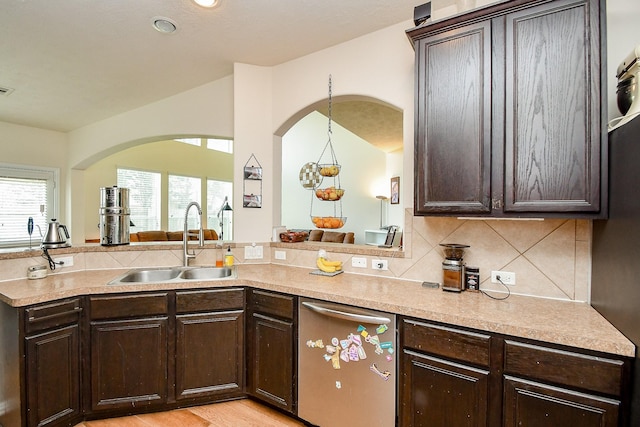 2818 Lakecrest Forest Dr, Katy, TX 77493 - kitchen with a sink, stainless steel dishwasher, arched walkways, dark brown cabinets, and tasteful backsplash