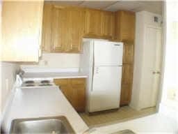 2207 S Braeswood Blvd S Unit 43B, Houston, TX 77030 - kitchen with freestanding refrigerator, light countertops, brown cabinetry, and a sink