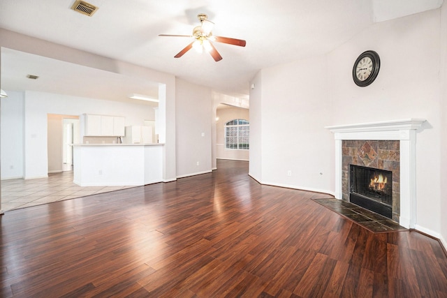 312 Cedar Branch Dr, League City, TX 77573 - unfurnished living room featuring a ceiling fan, a tiled fireplace, wood finished floors, and arched walkways