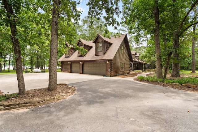 19314 Indigo Lake Dr, Magnolia, TX 77355 - view of front of house with log exterior, concrete driveway, and a garage