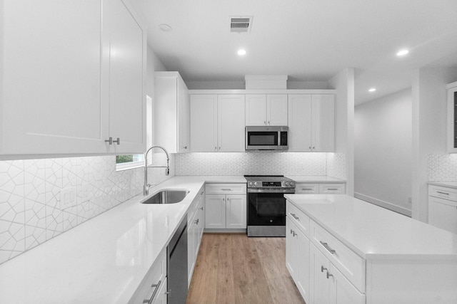 12219 Browning Dr, Montgomery, TX 77356 - kitchen with stainless steel appliances, a sink, recessed lighting, light wood finished floors, and a center island