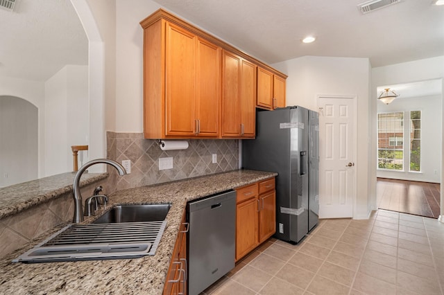 2113 Midway Ct, League City, TX 77573 - kitchen with stainless steel appliances, arched walkways, a sink, light stone counters, and light tile patterned floors