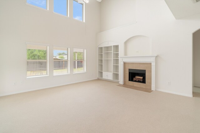 2113 Midway Ct, League City, TX 77573 - unfurnished living room featuring a towering ceiling, a fireplace, carpet, built in shelves, and baseboards