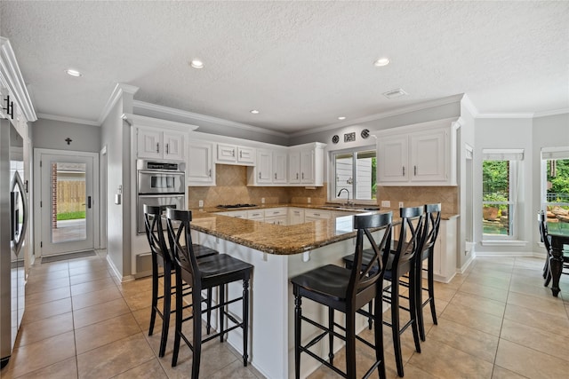 5902 Cardinal Creek Way, Kingwood, TX 77345 - kitchen with light tile patterned floors, appliances with stainless steel finishes, tasteful backsplash, a breakfast bar area, and recessed lighting