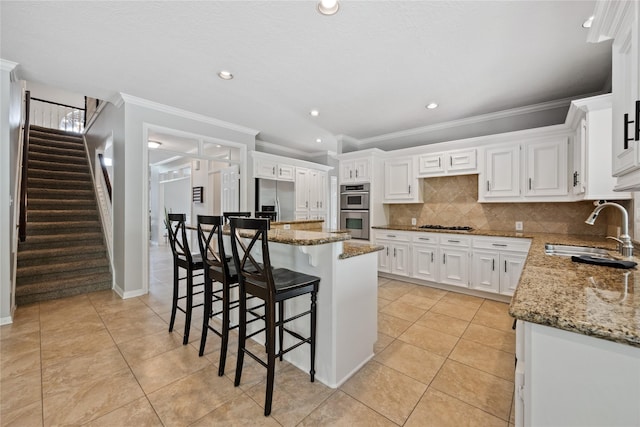 5902 Cardinal Creek Way, Kingwood, TX 77345 - kitchen featuring a sink, appliances with stainless steel finishes, ornamental molding, light stone counters, and a kitchen breakfast bar
