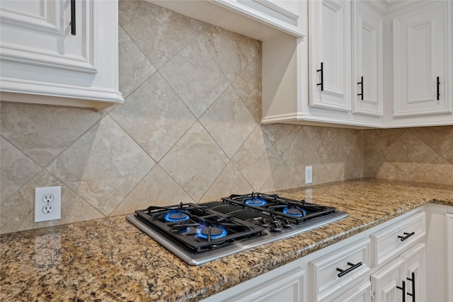 5902 Cardinal Creek Way, Kingwood, TX 77345 - kitchen featuring stovetop with downdraft, white cabinetry, light stone countertops, and decorative backsplash