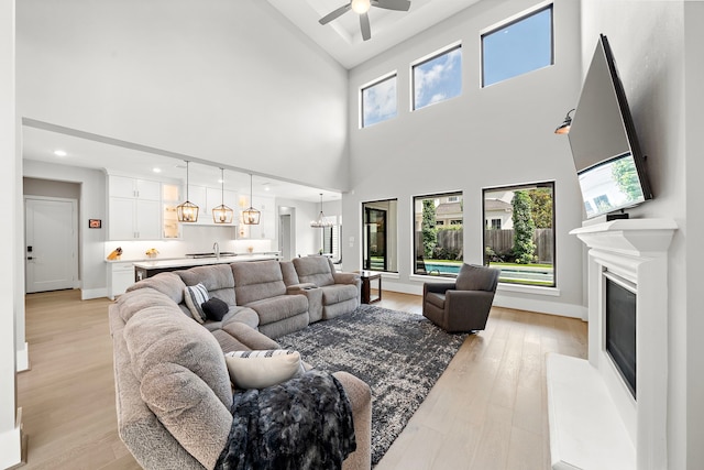 1610 Woodcrest Dr, Houston, TX 77018 - living room featuring a towering ceiling, light wood-type flooring, ceiling fan, a glass covered fireplace, and baseboards