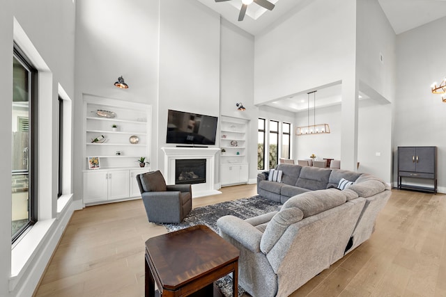 1610 Woodcrest Dr, Houston, TX 77018 - living room featuring a high ceiling, a chandelier, light wood finished floors, a glass covered fireplace, and a ceiling fan