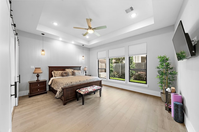 1610 Woodcrest Dr, Houston, TX 77018 - bedroom with a raised ceiling, a barn door, light wood-style flooring, baseboards, and recessed lighting