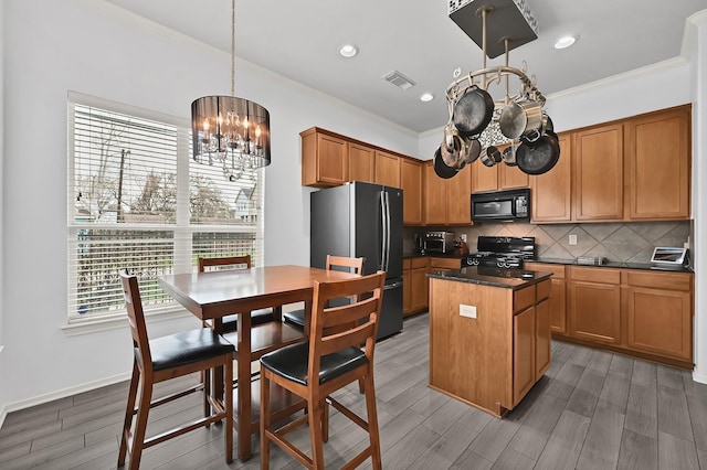 2602 Shady Acres Ct, Houston, TX 77008 - kitchen with black microwave, a chandelier, freestanding refrigerator, range with gas cooktop, and a kitchen island