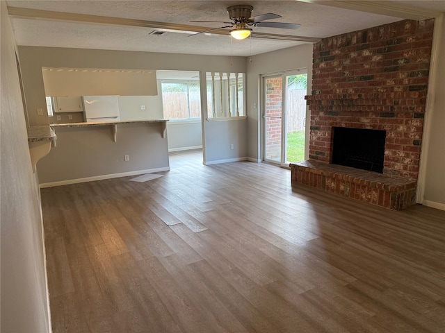 12819 Labelle Ln, Houston, TX 77015 - unfurnished living room featuring baseboards, a ceiling fan, wood finished floors, a textured ceiling, and a brick fireplace