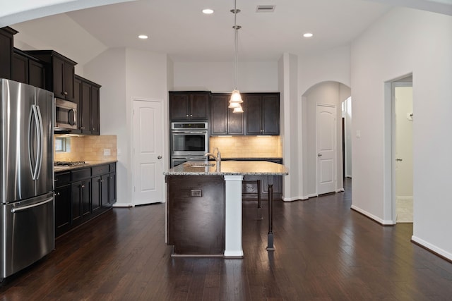 253 Dove Meadow Dr, Conroe, TX 77384 - kitchen with stainless steel appliances, arched walkways, vaulted ceiling, tasteful backsplash, and light stone counters