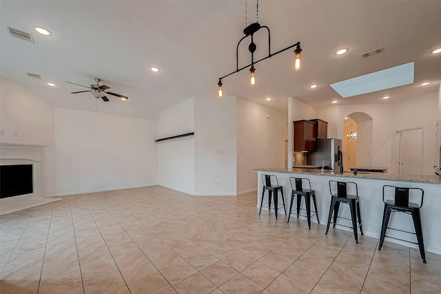 5339 Glenfield Spring Ln, Spring, TX 77389 - kitchen with a breakfast bar area, stainless steel refrigerator with ice dispenser, ceiling fan, light stone counters, and open floor plan