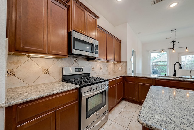 5339 Glenfield Spring Ln, Spring, TX 77389 - kitchen featuring stainless steel appliances, a sink, brown cabinetry, light stone countertops, and backsplash