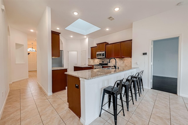 5339 Glenfield Spring Ln, Spring, TX 77389 - kitchen featuring appliances with stainless steel finishes, a sink, light tile patterned floors, a skylight, and recessed lighting