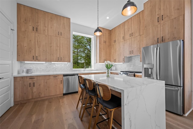 5705 Dolores St Unit B, Houston, TX 77057 - kitchen with stainless steel appliances, light stone countertops, light wood-type flooring, tasteful backsplash, and a breakfast bar area