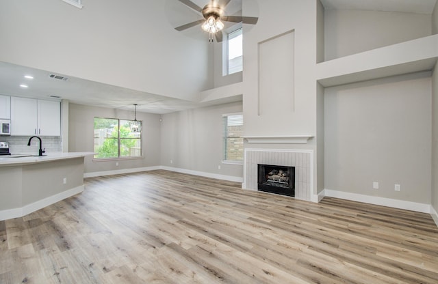 5238 Timber Quail Dr, Humble, TX 77346 - unfurnished living room with high vaulted ceiling, ceiling fan, a fireplace, light wood-type flooring, and baseboards