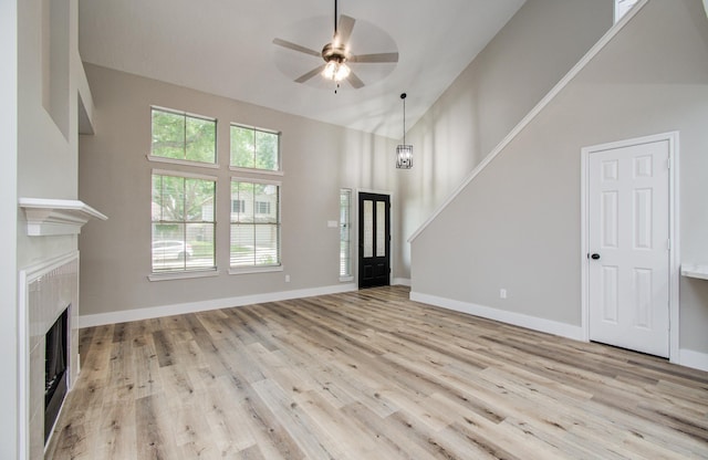 5238 Timber Quail Dr, Humble, TX 77346 - unfurnished living room with a ceiling fan, light wood-style flooring, a fireplace, baseboards, and high vaulted ceiling