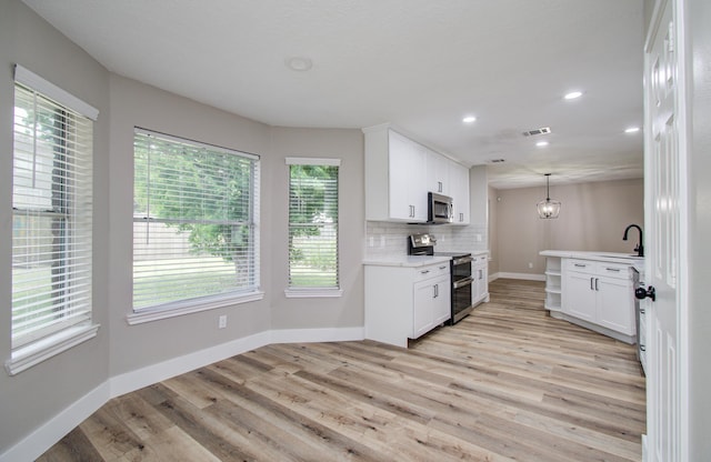 5238 Timber Quail Dr, Humble, TX 77346 - kitchen with stainless steel appliances, baseboards, light countertops, light wood-type flooring, and white cabinetry