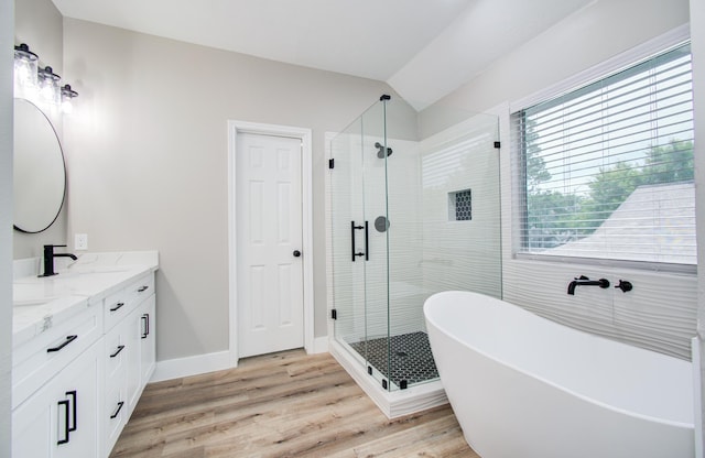 5238 Timber Quail Dr, Humble, TX 77346 - bathroom featuring double vanity, a freestanding tub, a shower stall, wood finished floors, and vaulted ceiling