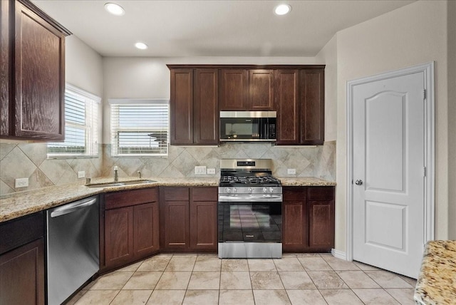 2114 Sand Ridge Dr, Texas City, TX 77568 - kitchen with stainless steel appliances, a sink, light tile patterned flooring, dark brown cabinets, and decorative backsplash