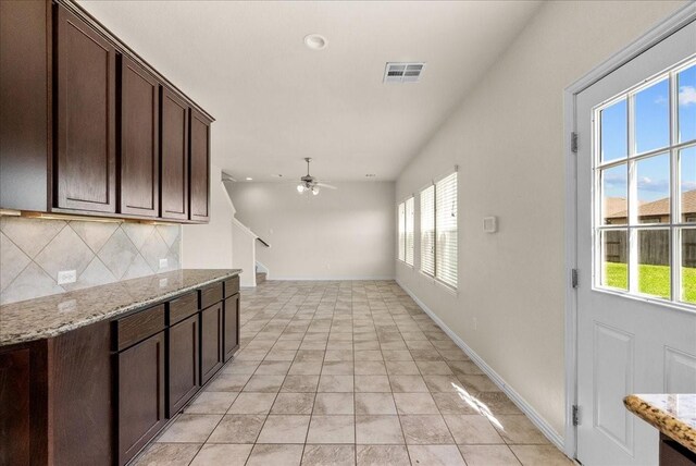 2114 Sand Ridge Dr, Texas City, TX 77568 - kitchen featuring decorative backsplash, dark brown cabinetry, a ceiling fan, light stone counters, and baseboards