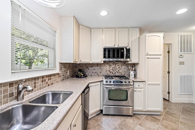 2510 Cypress Dr, Galveston, TX 77551 - kitchen featuring stainless steel appliances, a sink, backsplash, light stone counters, and recessed lighting
