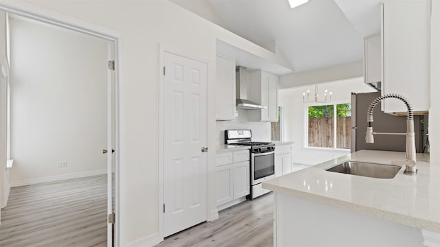 24006 Scrivener Ln, Katy, TX 77493 - kitchen featuring stainless steel gas range, wall chimney range hood, a sink, vaulted ceiling, and light wood-type flooring