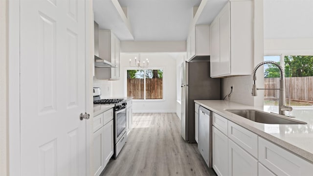 24006 Scrivener Ln, Katy, TX 77493 - kitchen with appliances with stainless steel finishes, a sink, decorative backsplash, light wood-style floors, and wall chimney exhaust hood