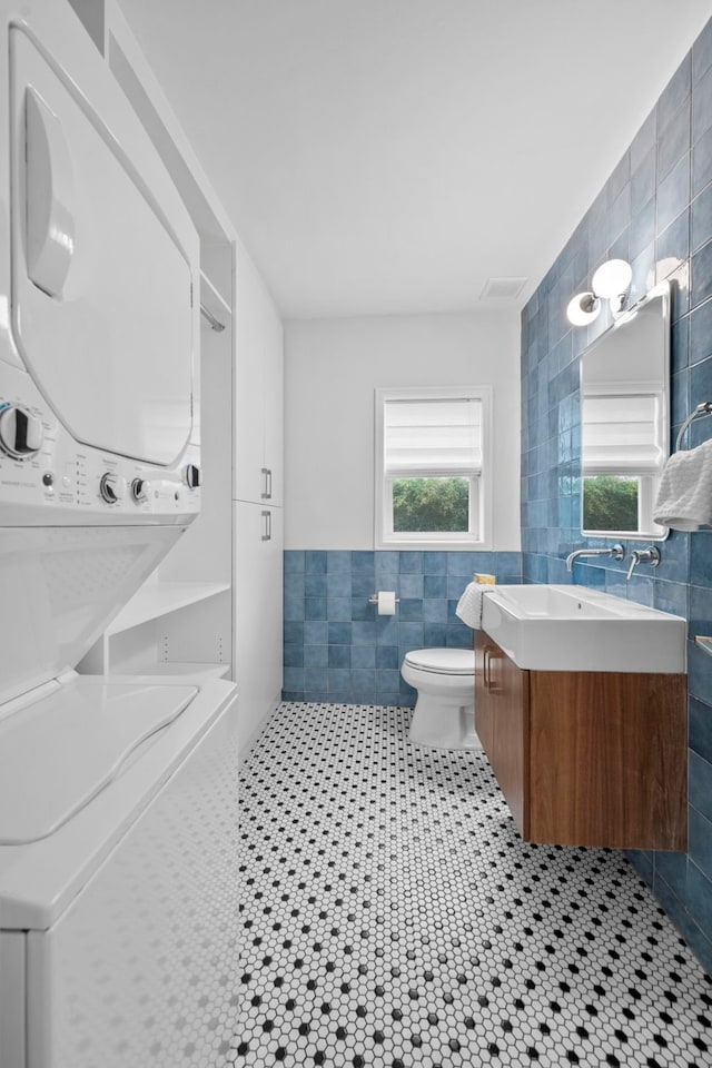 2101 Banks St, Houston, TX 77098 - bathroom with tile walls, stacked washer / drying machine, vanity, toilet, and tile patterned flooring