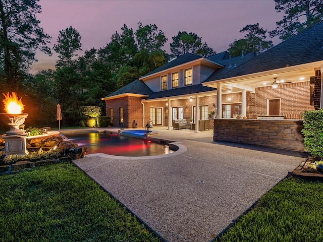 9810 Clubhouse Cir, Magnolia, TX 77354 - back of property at dusk with a patio, brick siding, an outdoor pool, and roof with shingles